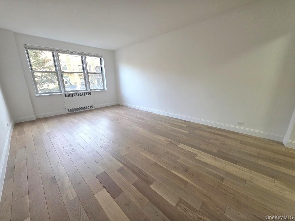 35-21 79th Street, Unit 4M Queens, NY 11372 - Photo 1 of 11 an empty room with wooden floor and windows