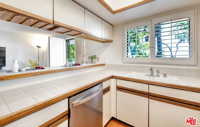 a kitchen with kitchen island a large window cabinets a sink and stainless steel appliances