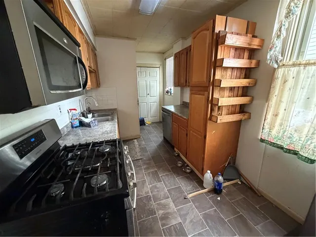 a kitchen with stainless steel appliances granite countertop a sink stove refrigerator and cabinets