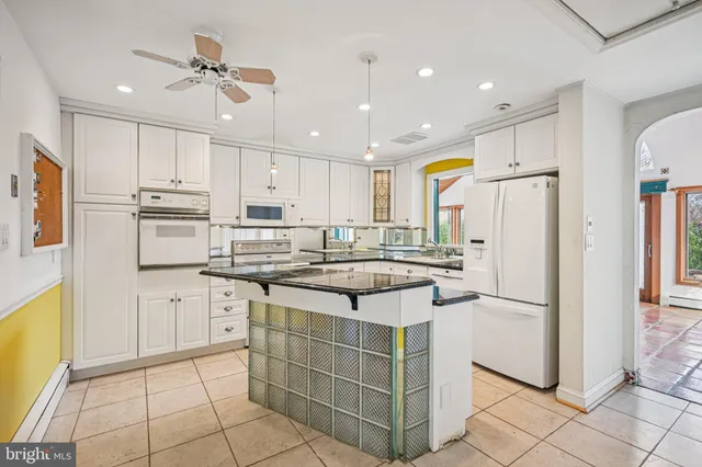 a kitchen with stainless steel appliances granite countertop a refrigerator a sink dishwasher a stove a dining table and chairs with wooden floor