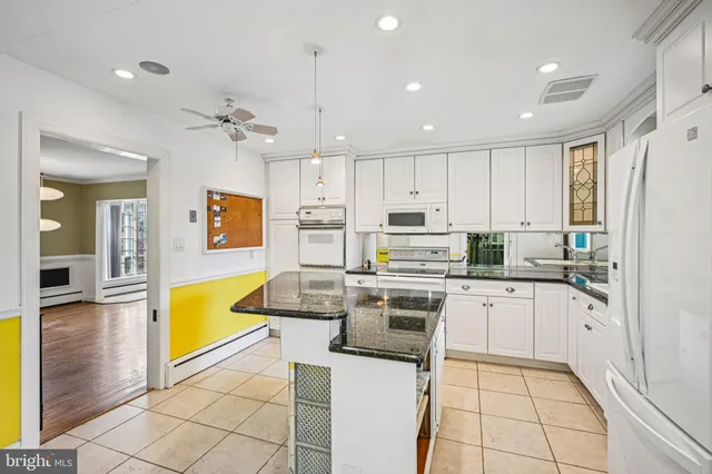 a kitchen with stainless steel appliances granite countertop a stove top oven a sink dishwasher and white cabinets with wooden floor