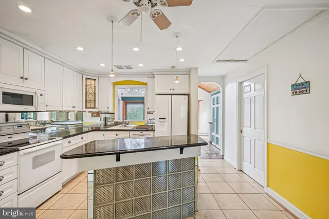 a large white kitchen with a large window and stainless steel appliances