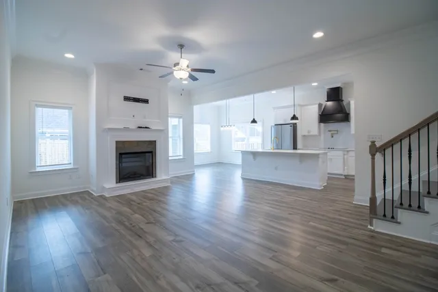 an empty room with wooden floor fireplace and windows