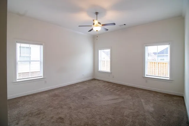 an empty room with windows and fan