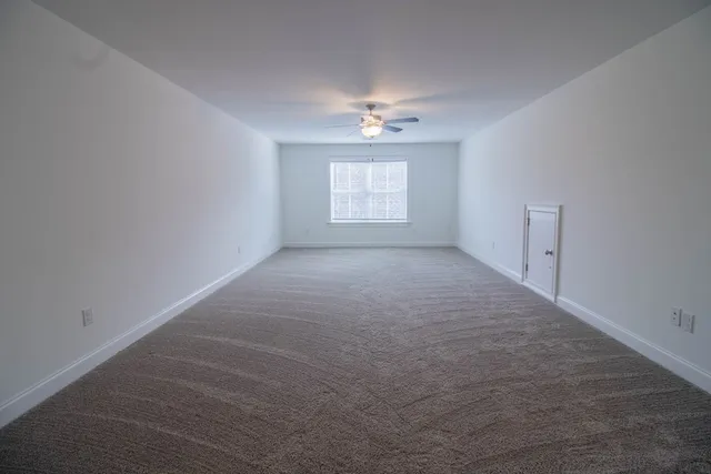 en empty room with windows and ceiling fan