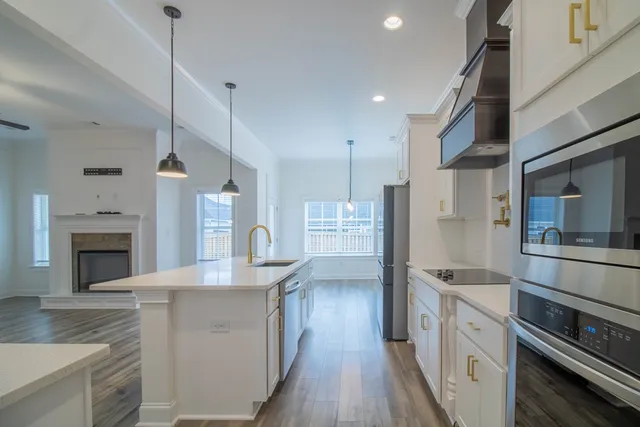 a kitchen with stainless steel appliances granite countertop a refrigerator a oven and white cabinets with wooden floors