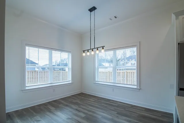 a view of an empty room with wooden floor and windows