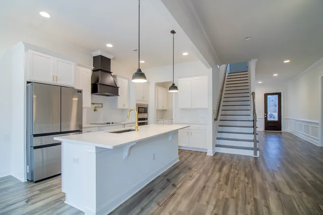 a large kitchen with a center island wooden floor stainless steel appliances and wooden floor