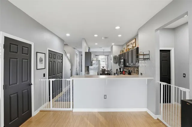 a view of a kitchen with kitchen island granite countertop wooden floor and stainless steel appliances