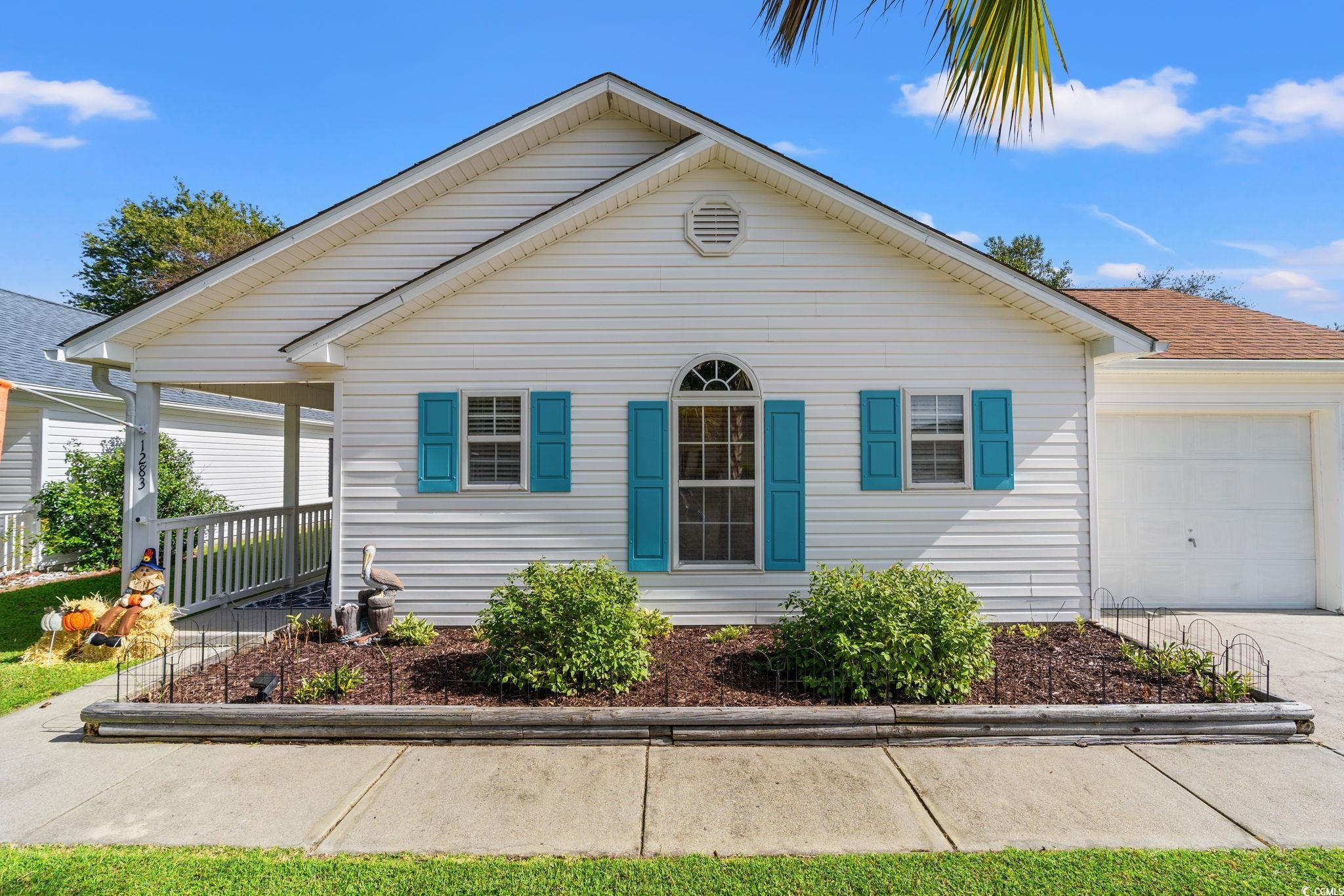 View of front facade featuring an attached garage, covered porch, and driveway