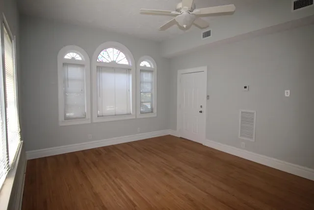 a view of an empty room with wooden floor and a window