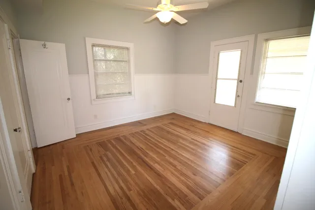a view of an empty room with wooden floor and a window