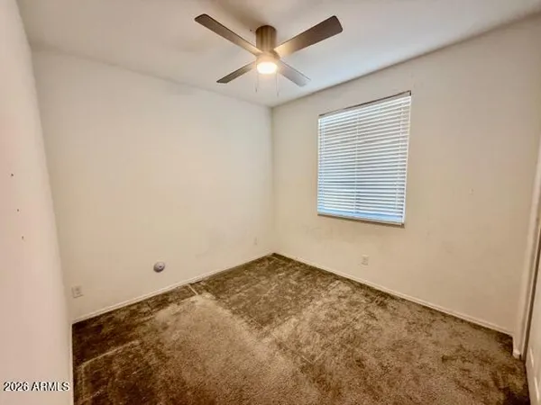 an empty room with a window and a ceiling fan