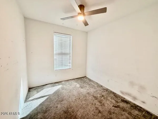an empty room with a window and a fan