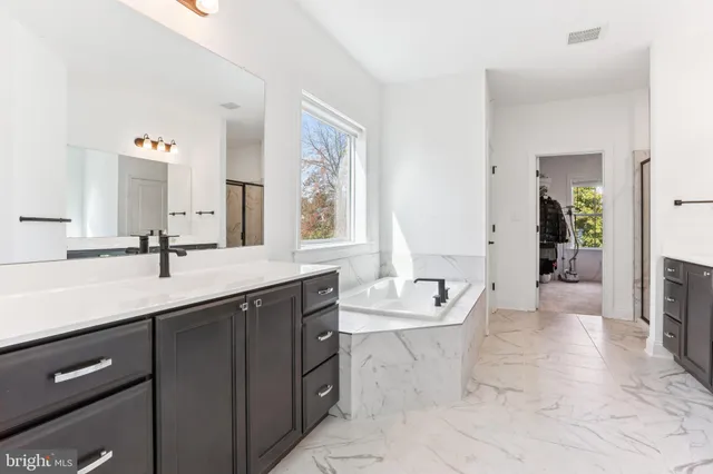 a spacious bathroom with a tub sink and mirror