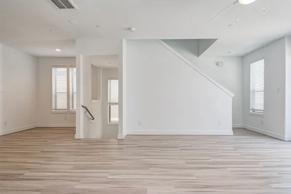 a view of empty room with wooden floor and fan