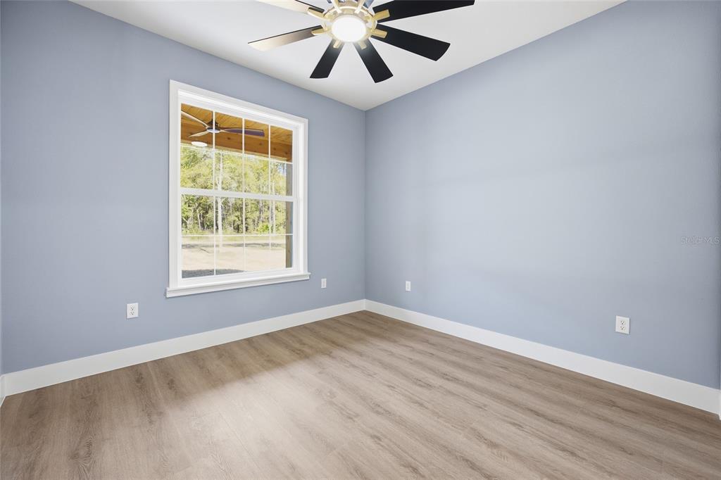 13186 Southwest 52nd Lane Road Ocala, FL 34481 - Photo 15 of 37 an empty room with wooden floor chandelier fan and windows