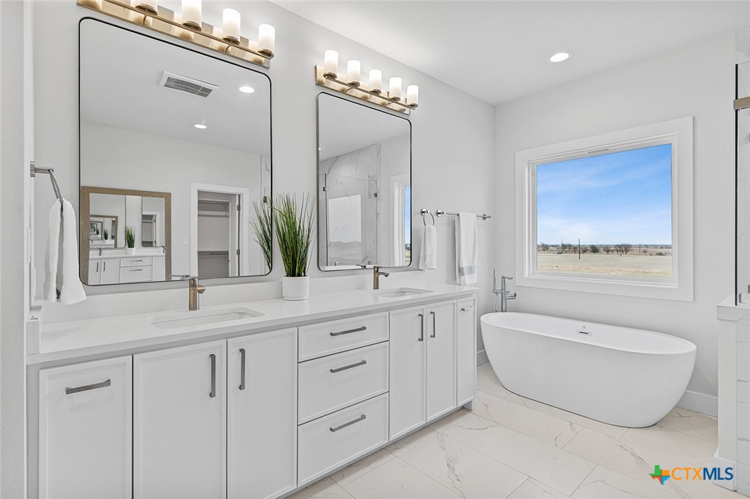 477 Willow Moon Ranch Road Crawford, TX 76638 - Photo 19 of 40 a spacious bathroom with a granite countertop sink and a mirror