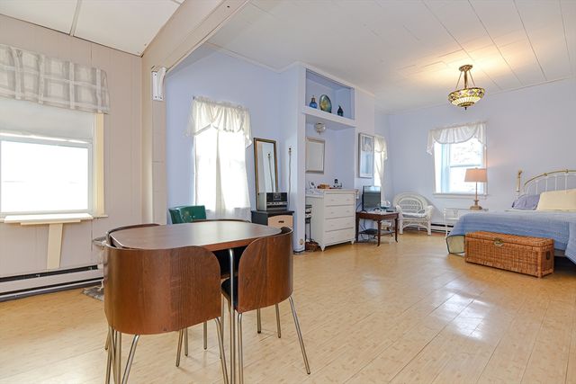 a living room with furniture and a dining table with wooden floor