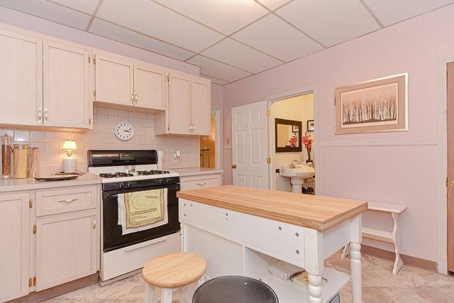 a kitchen with a stove a sink cabinets and a window