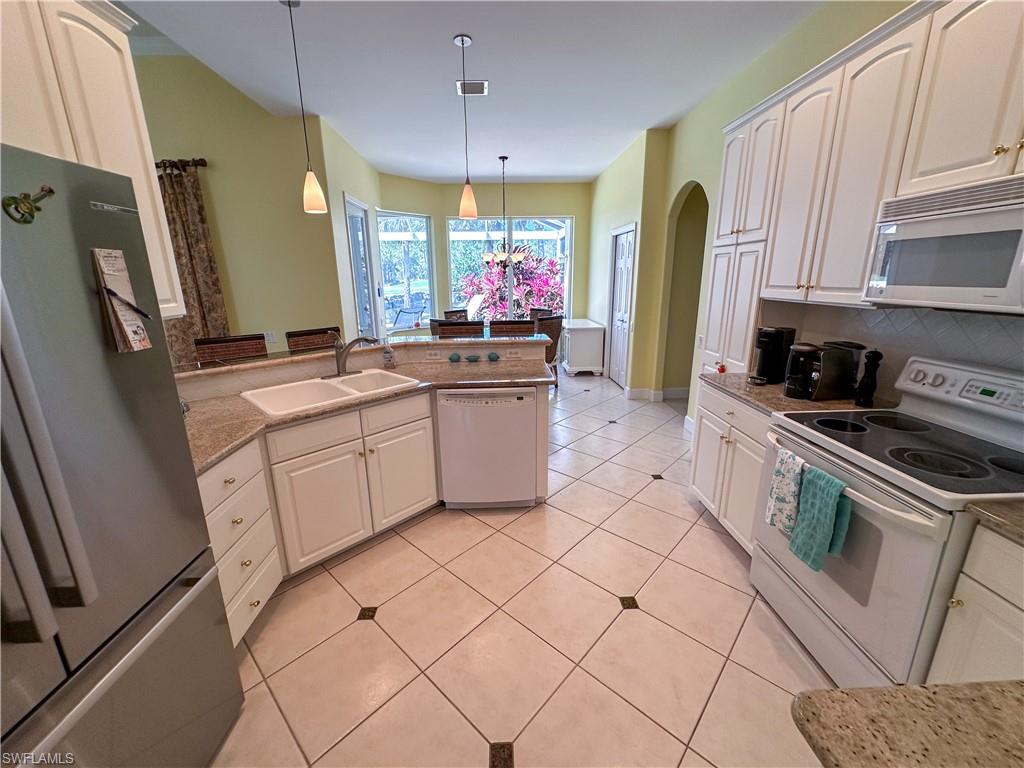 8229 Allendale Court Naples, FL 34120 - Photo 31 of 50 a kitchen with stainless steel appliances a sink stove refrigerator and cabinets