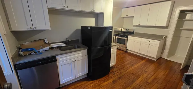 a kitchen with granite countertop white cabinets and black appliances