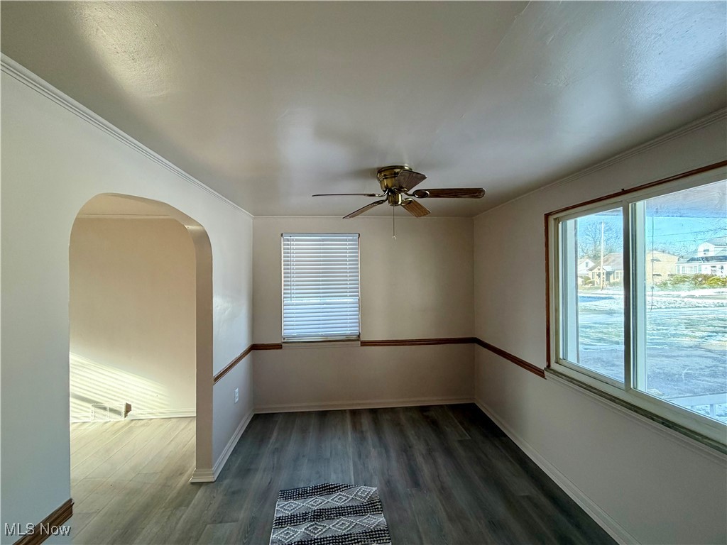 34 West Lewis Street Struthers, OH 44471 - Photo 7 of 14 Empty room featuring arched walkways, dark wood-style flooring, a ceiling fan, and healthy amount of natural light