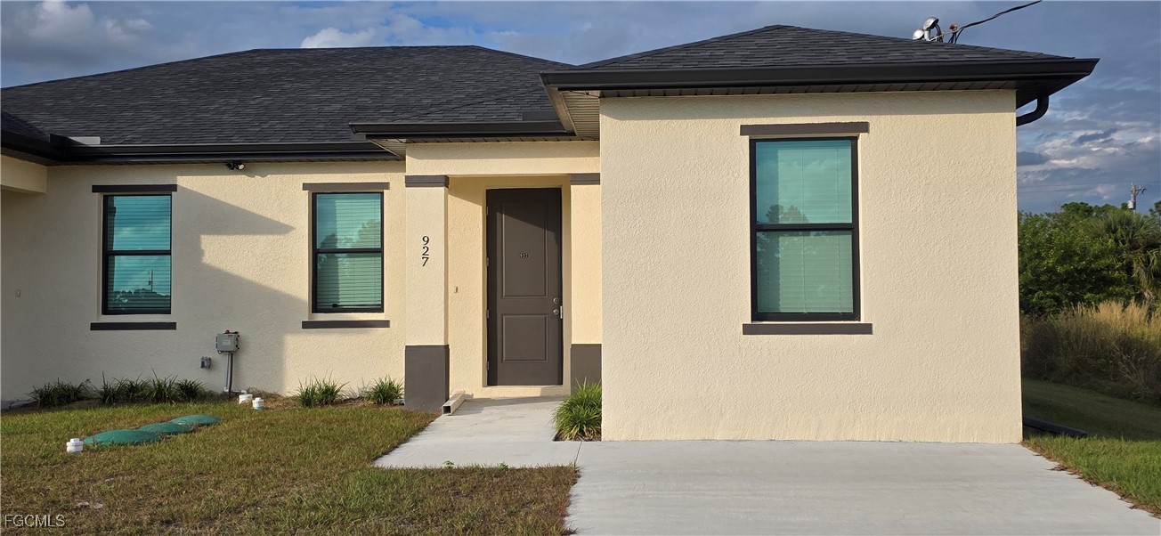 927 Chenault Street Lehigh Acres, FL 33974 - Photo 1 of 16 a front view of a house with garden