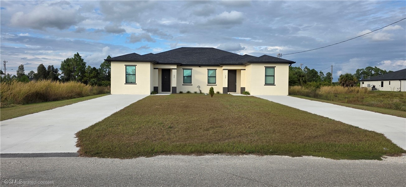 927 Chenault Street Lehigh Acres, FL 33974 - Photo 3 of 16 a front view of a house with garden