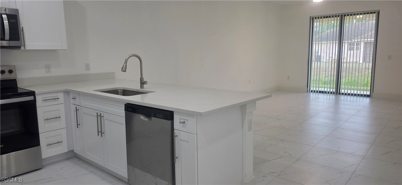 927 Chenault Street Lehigh Acres, FL 33974 - Photo 5 of 16 a kitchen with a sink cabinets and appliances