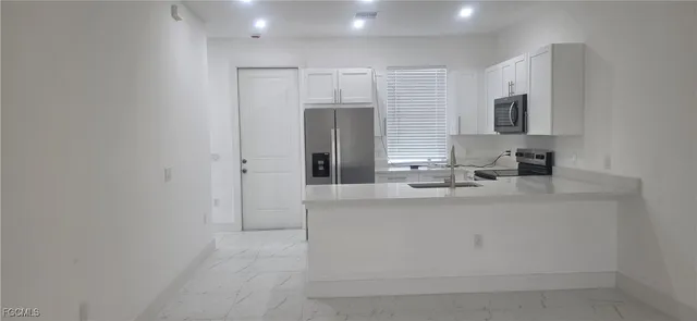 a large white kitchen with sink and stainless steel appliances