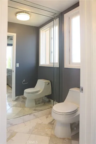 a white toilet sitting next to a chair and a window