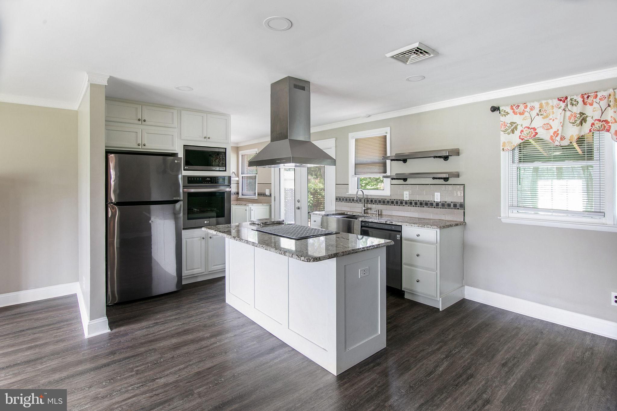 a kitchen with stainless steel appliances a sink a stove a refrigerator and wooden floor