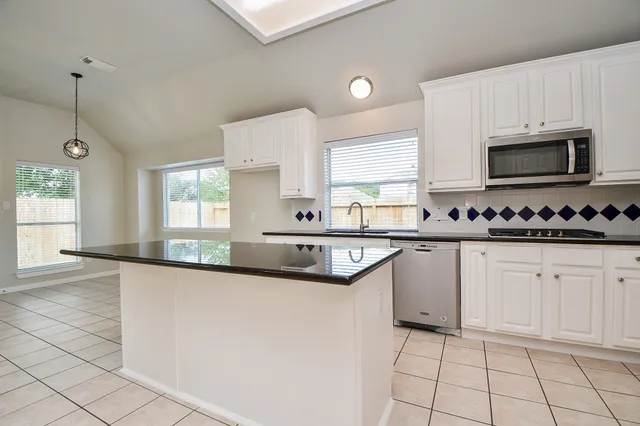 a kitchen with granite countertop a sink a stove top oven and cabinets
