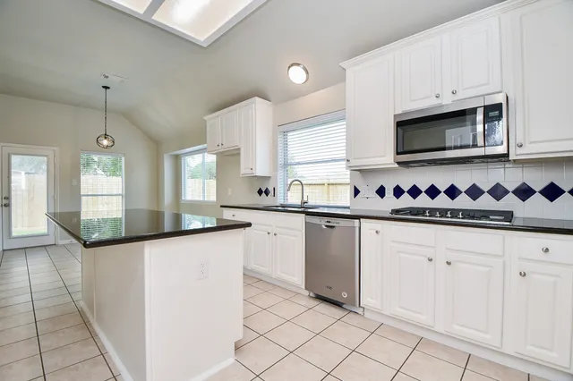 a kitchen with granite countertop white cabinets and white appliances