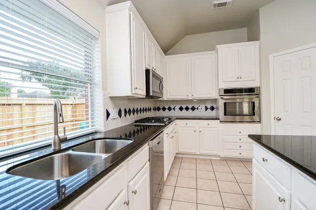 a kitchen with granite countertop a sink stove and cabinets