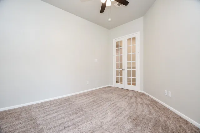 an empty room with window and chandelier fan
