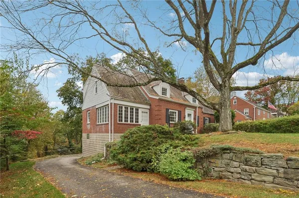 a view of a white house next to a yard with large trees
