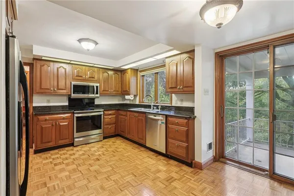 a large kitchen with stainless steel appliances granite countertop a stove top oven a sink and cabinets
