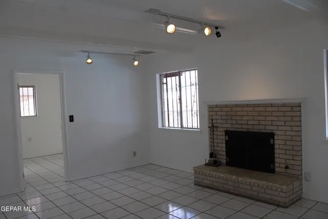 an empty room with windows and fireplace