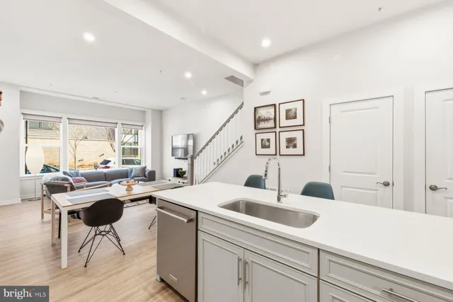 a kitchen with a sink a counter top space and living room view