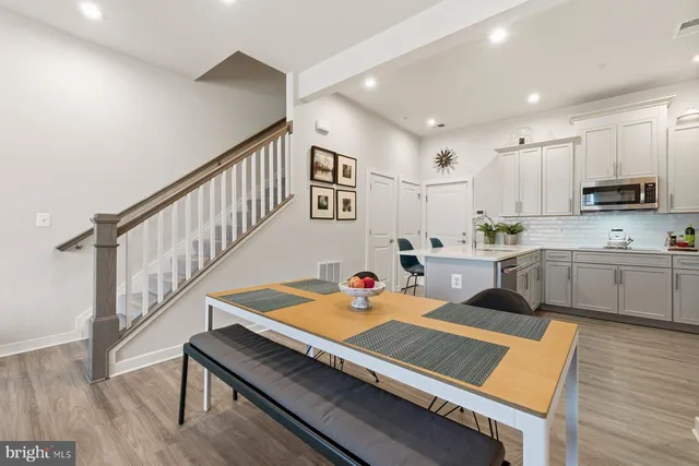 a open kitchen with white cabinets a sink dishwasher and a stove with wooden floor