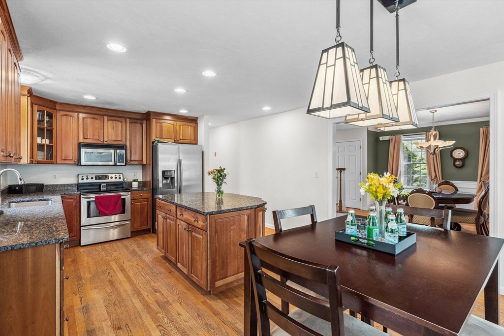 10 Falls Brook Road Hudson, MA 01749 - Photo 13 of 42 a kitchen with stainless steel appliances granite countertop a refrigerator a stove and a dining table with wooden floor