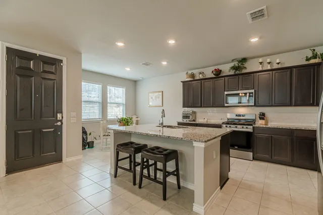 a kitchen with stainless steel appliances granite countertop a stove top oven a sink dishwasher and a refrigerator