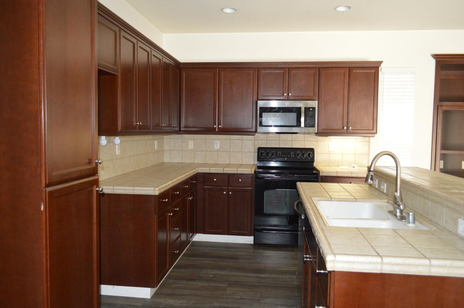 4227 Ivory Lane Turlock, CA 95382 - Photo 11 of 60 a kitchen with stainless steel appliances granite countertop wooden cabinets a stove top oven a sink and dishwasher