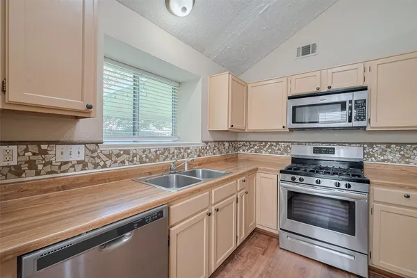 a kitchen with white cabinets appliances a sink and a window