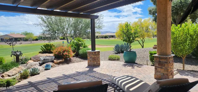 a view of a patio with table and chairs potted plants and floor to ceiling window
