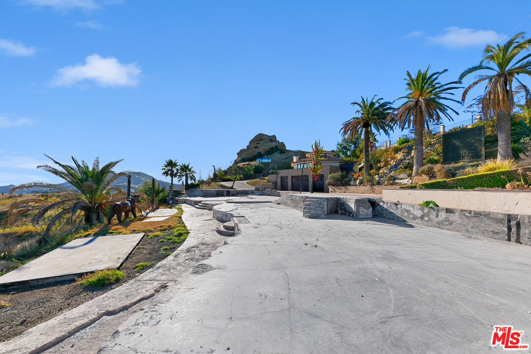 23000 Saddle Peak Road Topanga, CA 90290 - Photo 23 of 26 a view of a swimming pool with a lawn chairs under palm trees