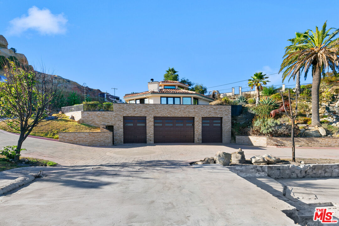 23000 Saddle Peak Road Topanga, CA 90290 - Photo 3 of 26 a front view of a house with a garden and patio