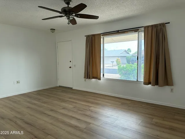 a view of an empty room with a window and wooden floor